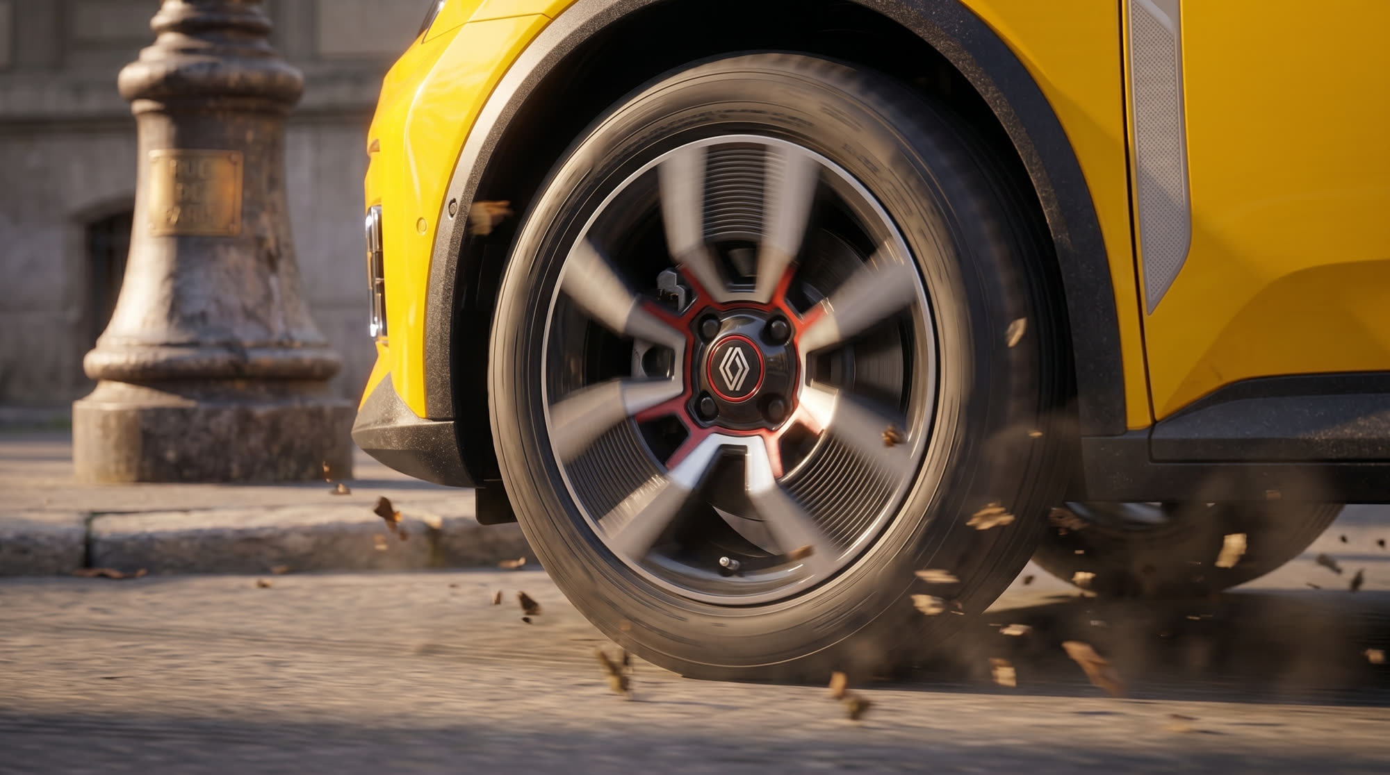 Close-up of a yellow car's wheel kicking up leaves